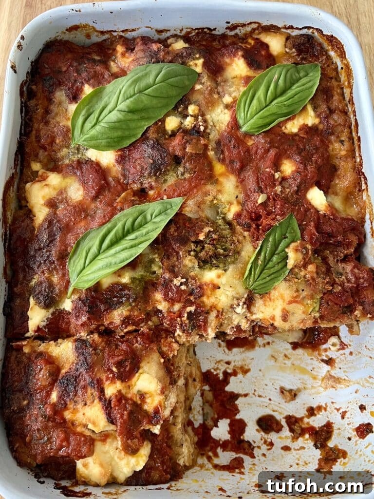 Zucchini Parmigiana with Ricotta: Layered Baked Zucchini Parmesan 3 The finished baked zucchini parmigiana (parmesan) in baking dish with basil garnish and one slice cut out.