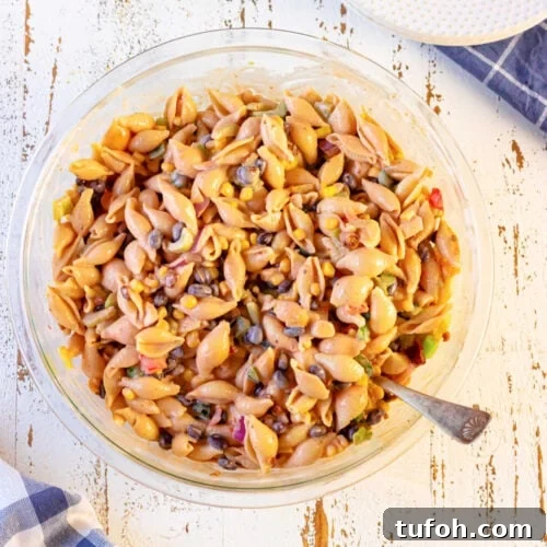 Closeup overhead view of the macaroni salad in a bowl with a spoon in it for serving.