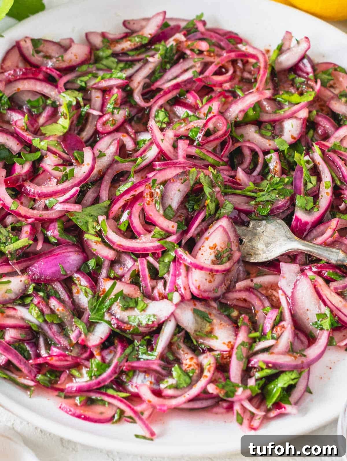Sumac onions with parsley on a white plate