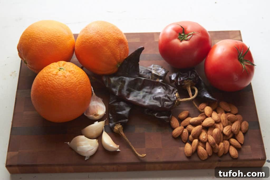Orange-Almond Mole Sauce: Quick Recipe for Vibrant Flavor 3 Ingredients for almond orange mole sauce: oranges, tomatoes, guajillo chiles, almonds and garlic displayed on a cutting board.