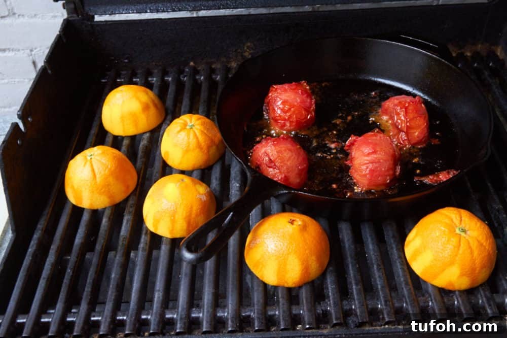 Orange-Almond Mole Sauce: Quick Recipe for Vibrant Flavor 4 Tomatoes in a cast iron skillet and orange halves all roasting on a grill.