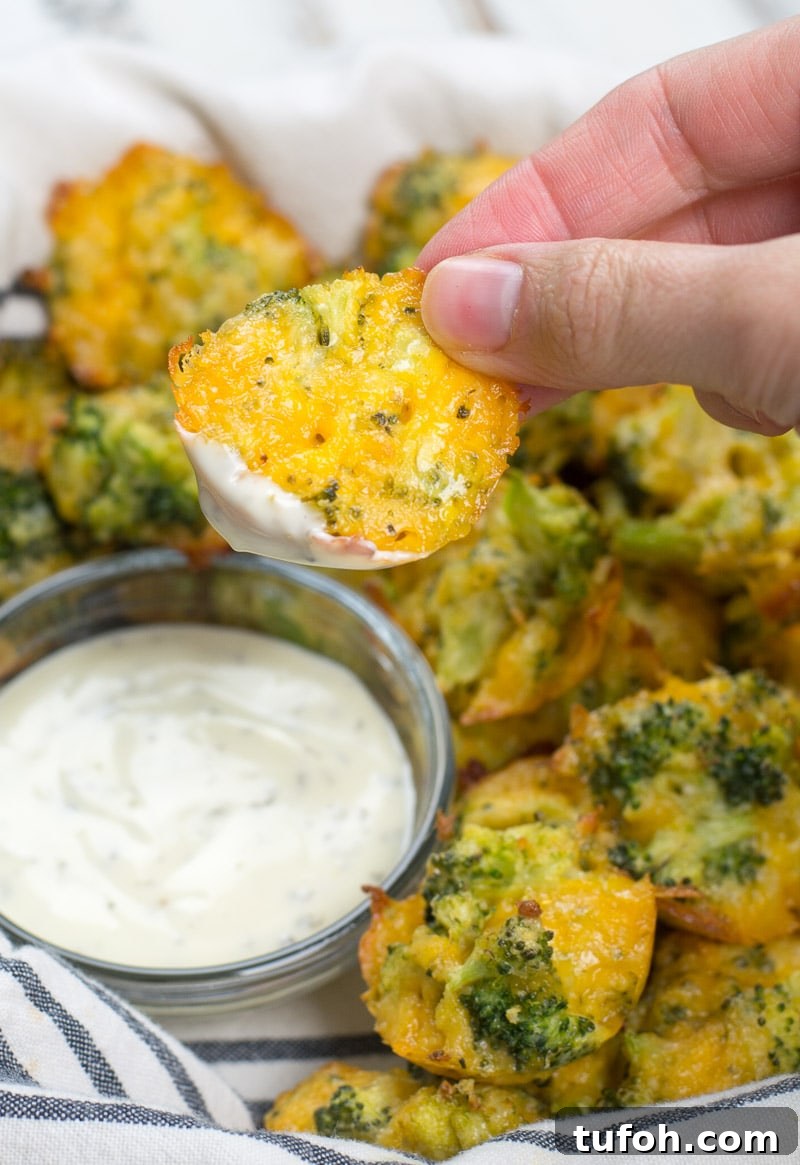 a keto broccoli and cheese bite being held above a dish of ranch dressing
