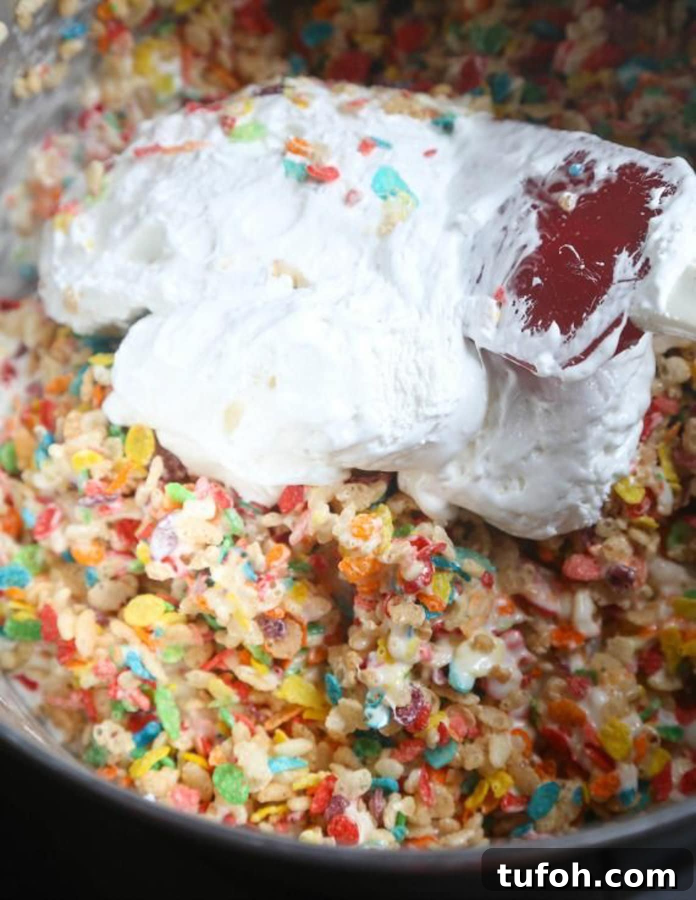 Fluff being added to a bowl of Krispie Treats mixture