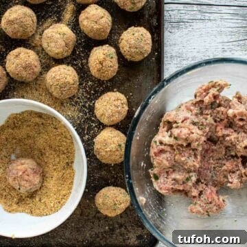 Meatballs mixture in a glass bowl, some meatballs rolled and coated in breadcrumbs.