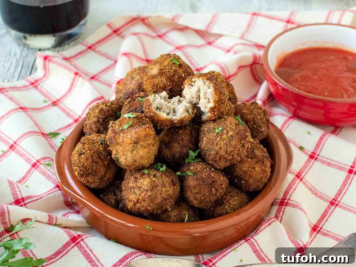 Meatball broken in half sitting on top of a pile of browned meatballs.