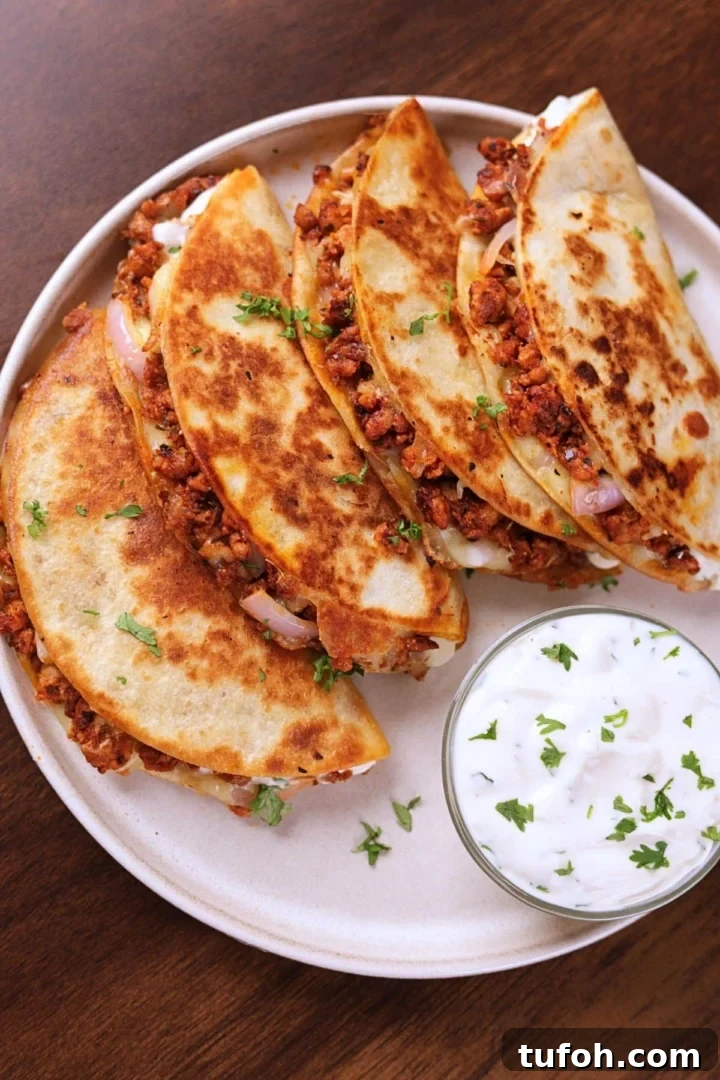 Crispy ground chicken tacos served on a white plate with creamy garlic sauce on the side.