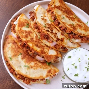 Crispy ground chicken tacos served on a white plate with creamy garlic sauce on the side.