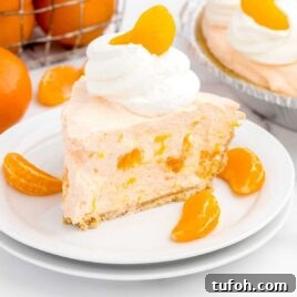 close up shot of a slice of pie topped with whipped cream and a mandarin orange on a plate
