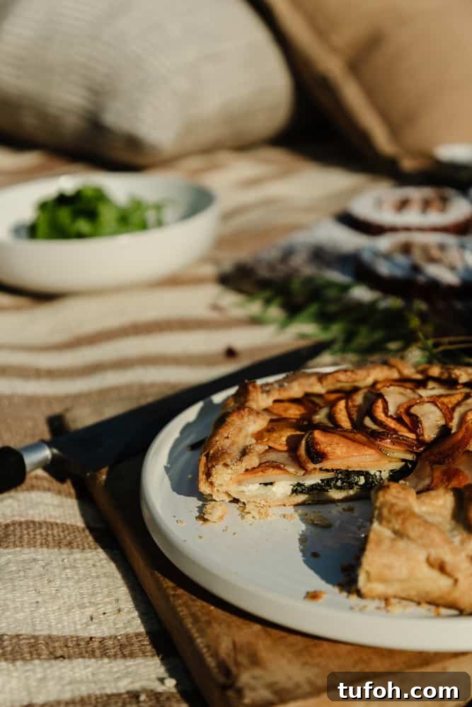 potato galette on a white plate on top of a rustic wood cutting board with a salad in the background
