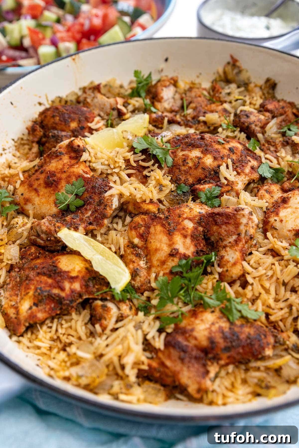 One pot Greek chicken and rice with lemon segments and parsley on top, and a light blue tea towel at the front of the pot.