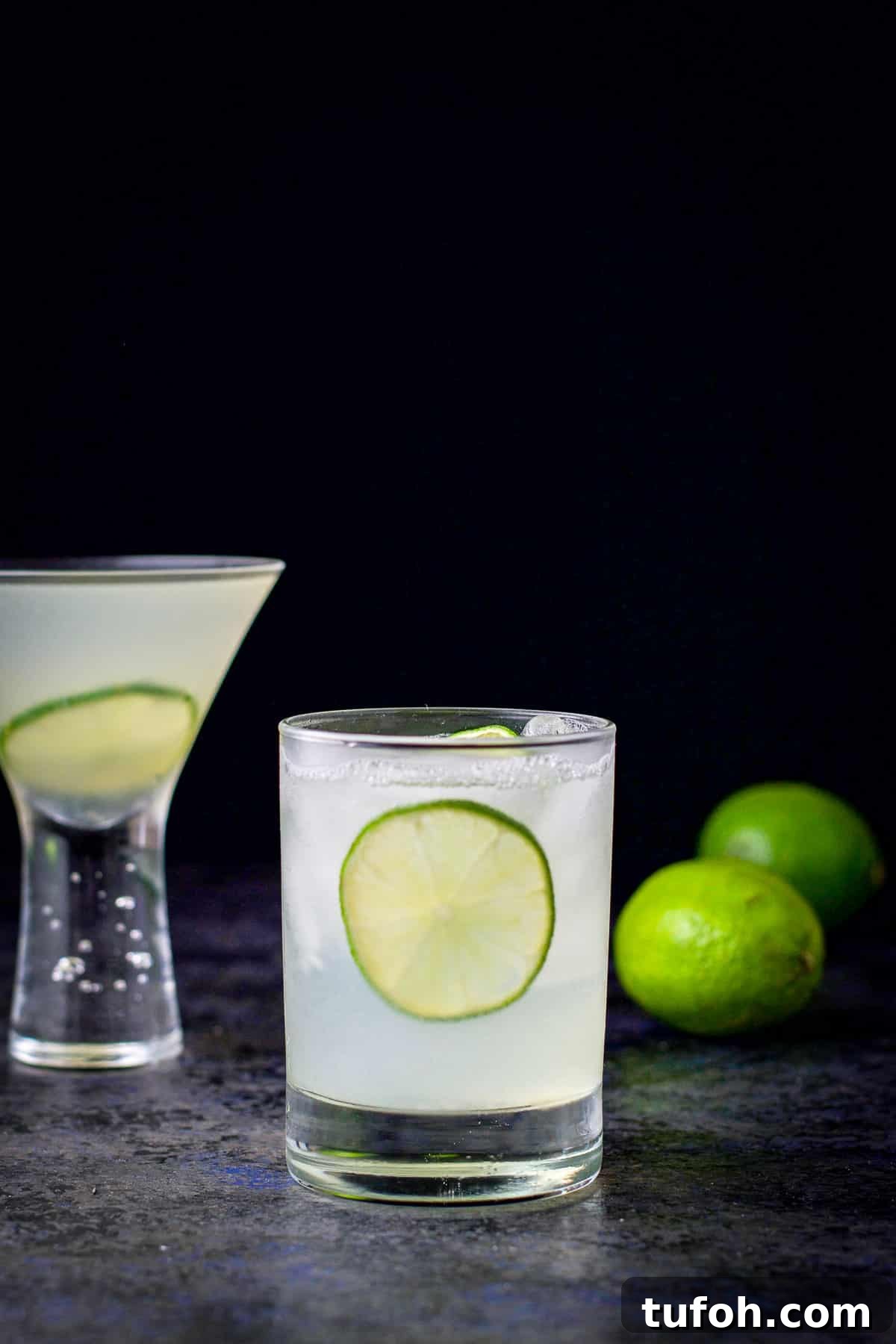 Double old fashioned glass of the vodka gimlet in front of the martini glass