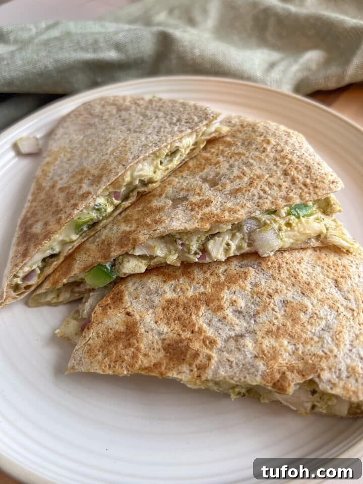Close-up shot of pesto chicken quesadillas on a plate next to a green kitchen towel