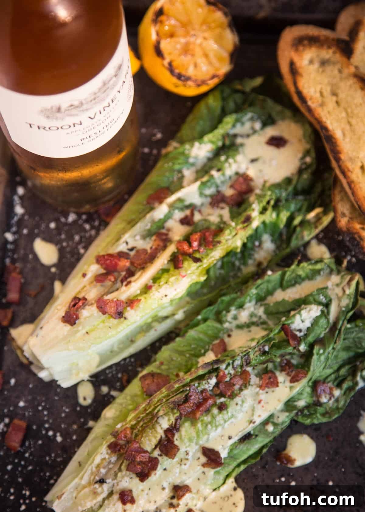 Grilled Caesar salad on a platter with a bottle of wine 