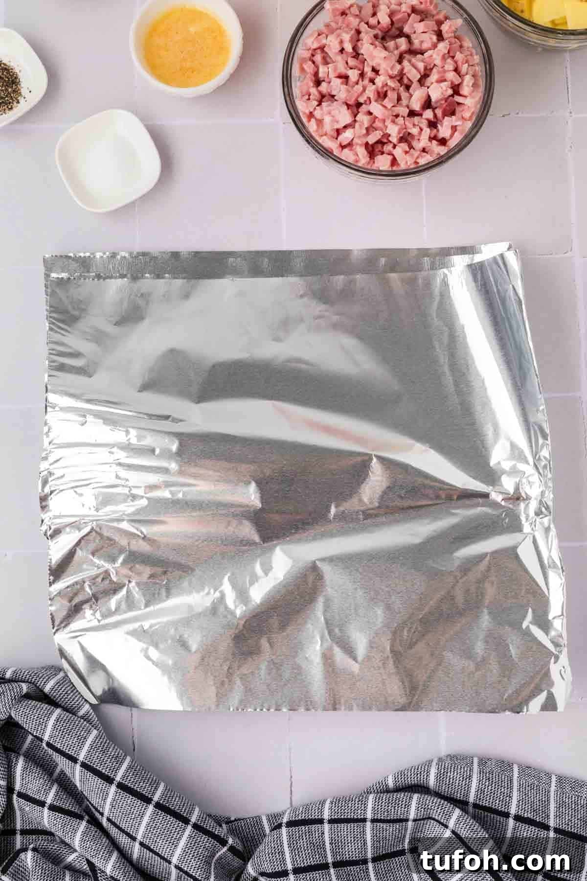 Slices of foil with small bowls of diced ham and spices on the side
