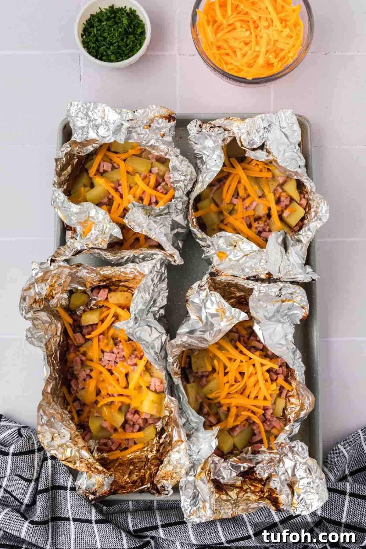 Ham and potato foil packets topped with shredded cheese