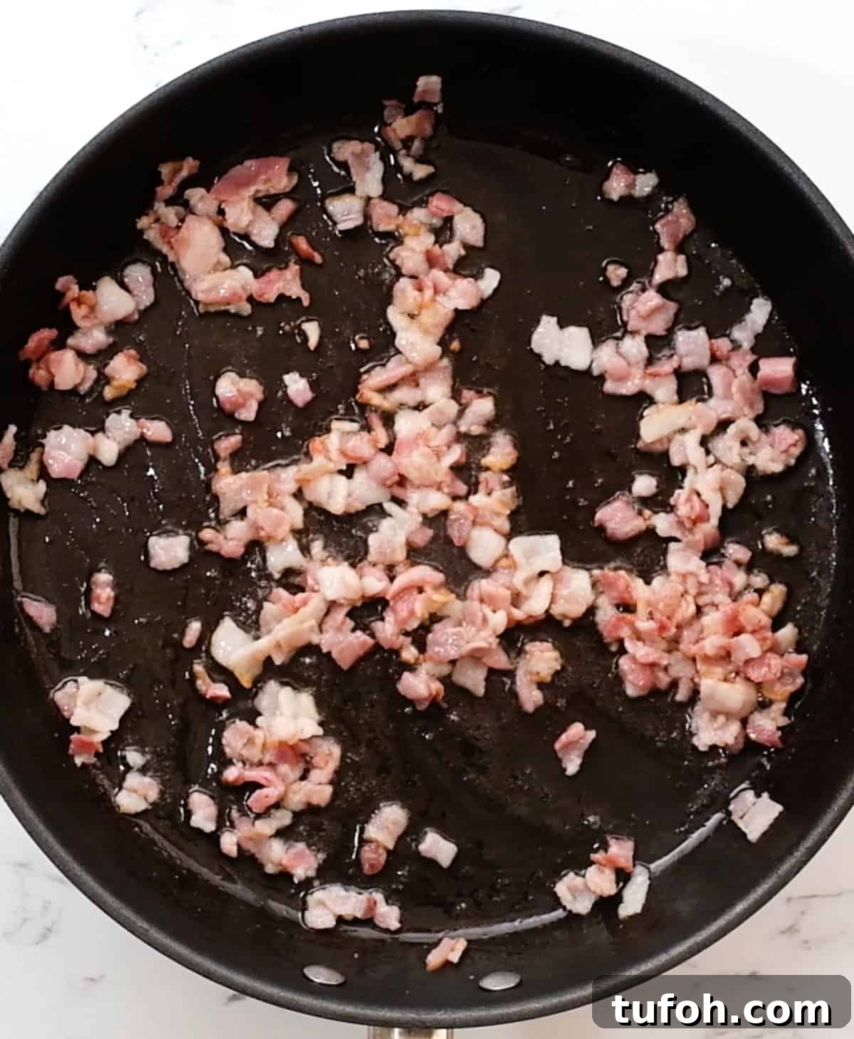 bacon in a fry pan after partially cooking