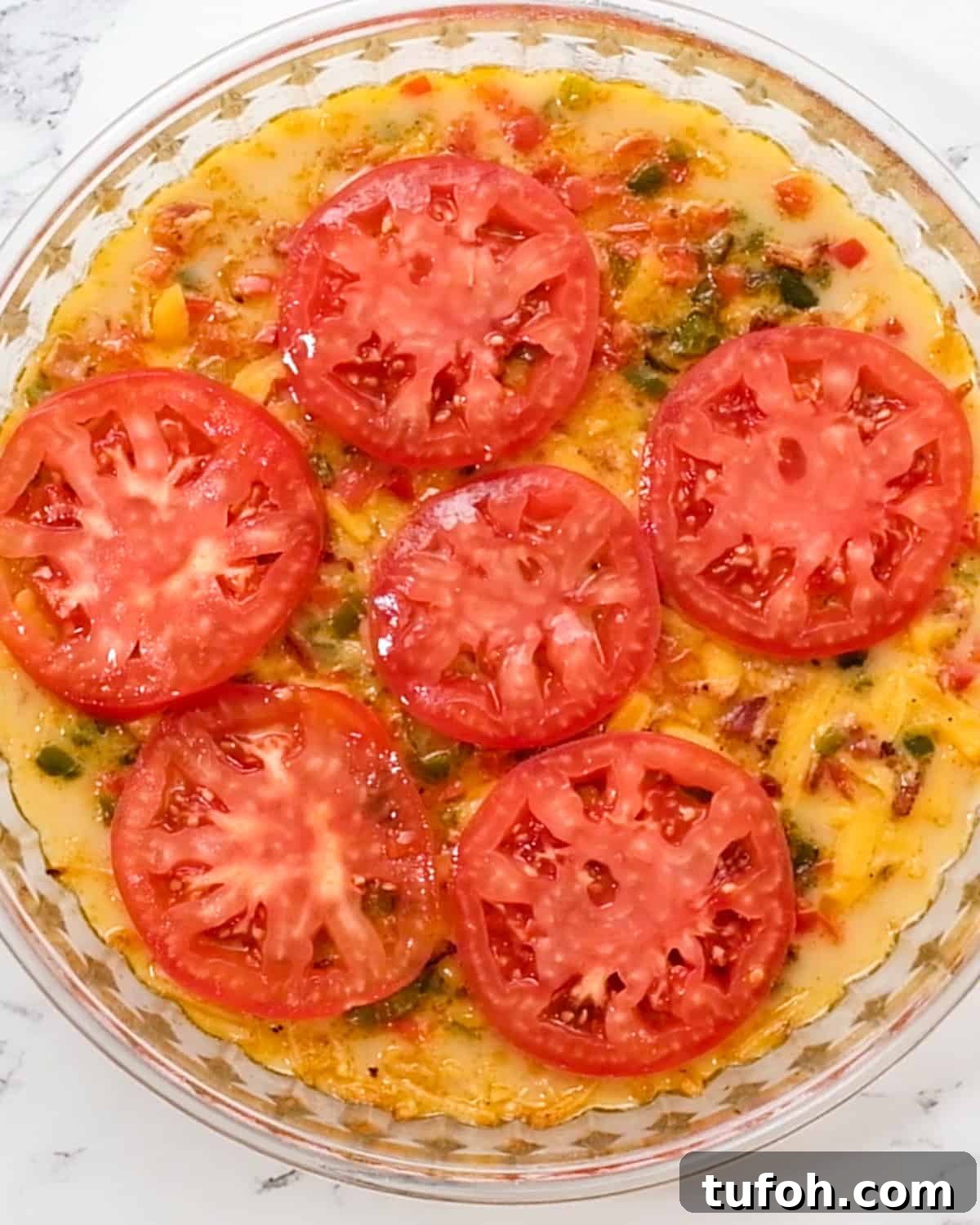 Hash Brown Crust Quiche topped with tomato slices before baking