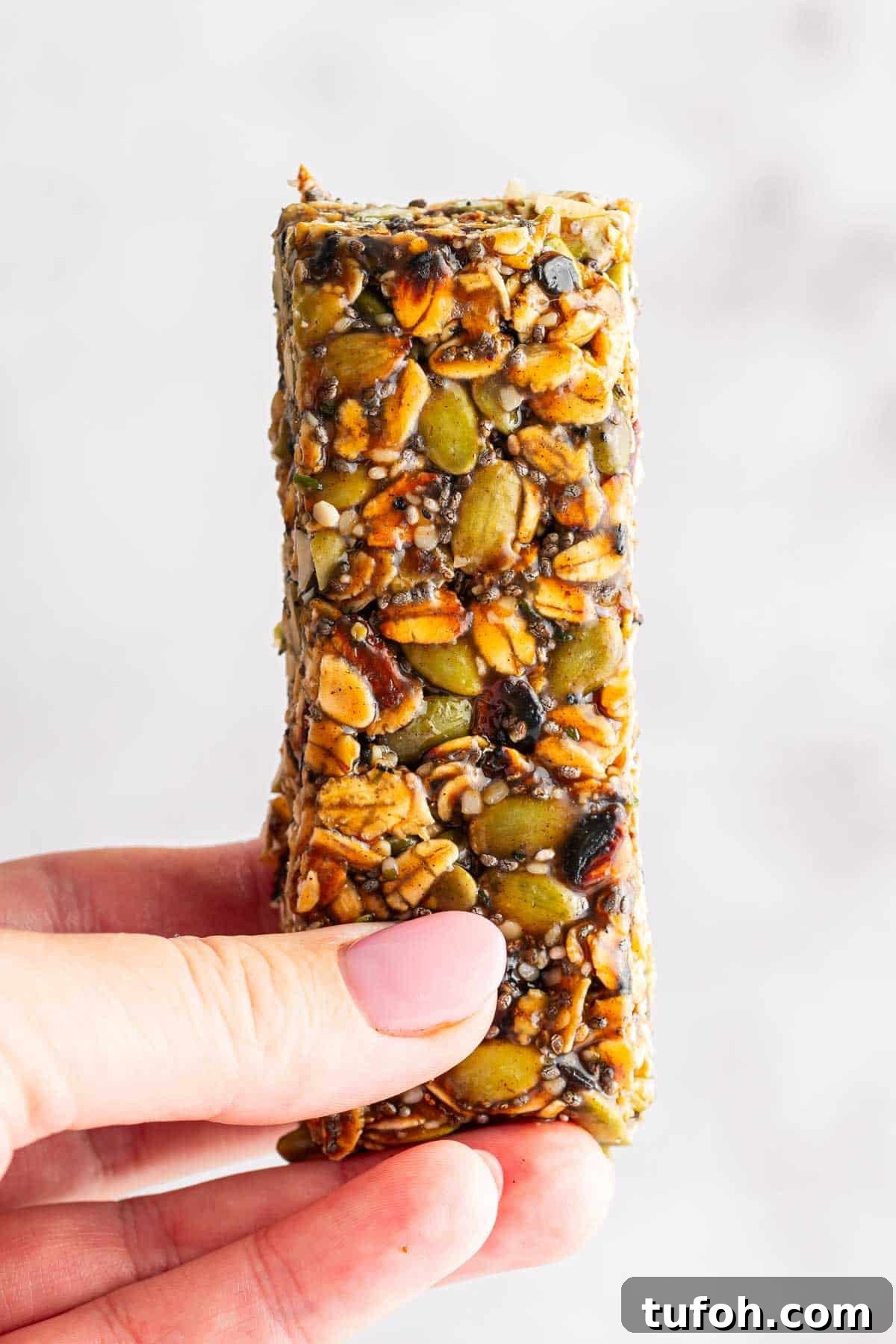 Hand holding a single no bake nut free granola bar.