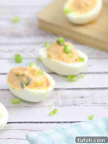 Kimchi spicy deviled eggs lined up with green onions on top.
