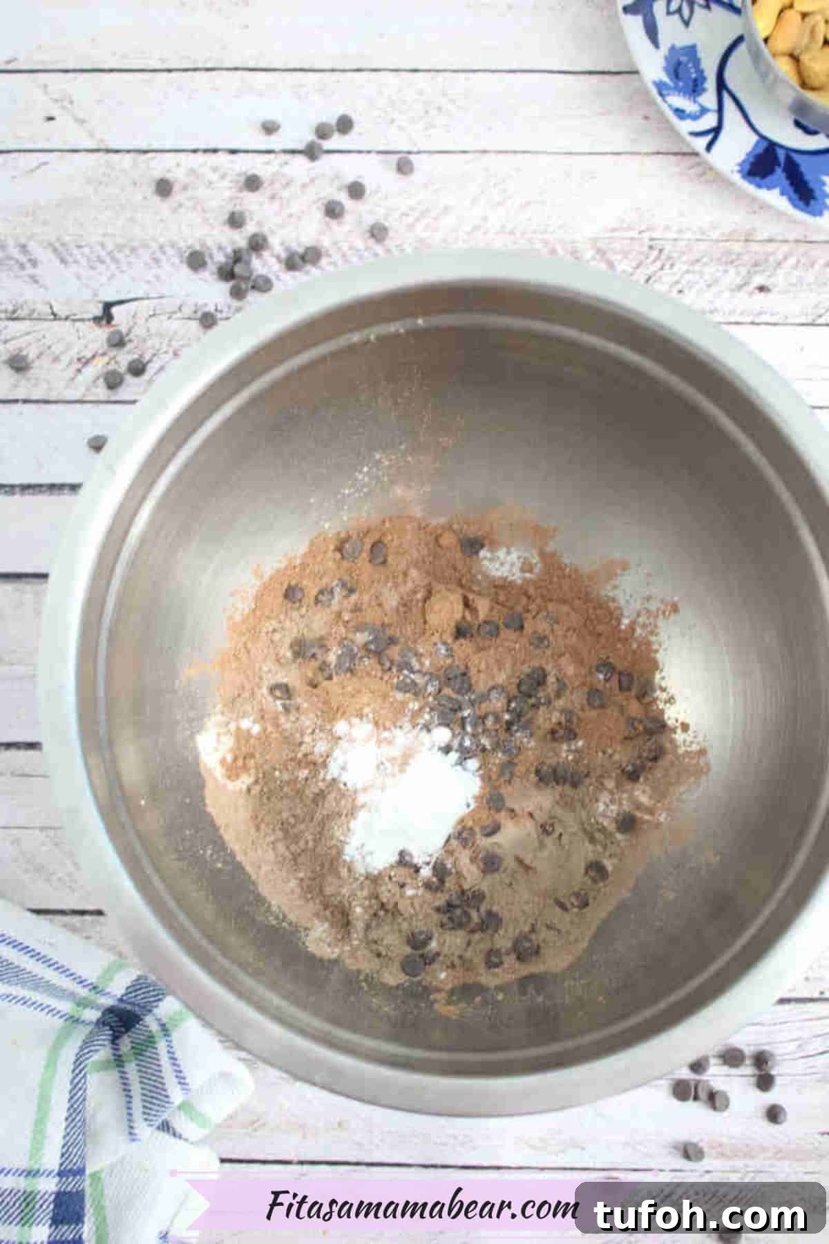 Steel bowl with protein powder, gluten-free flour, and chocolate chips in it.