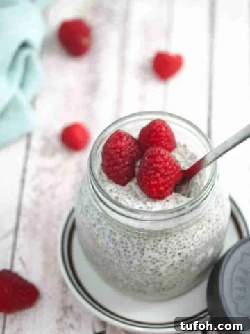 Keto chia pudding in a mason jar with raspberries on top.