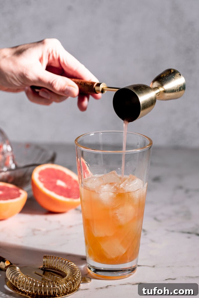 Adding grapefruit juice to a cocktail shaker.